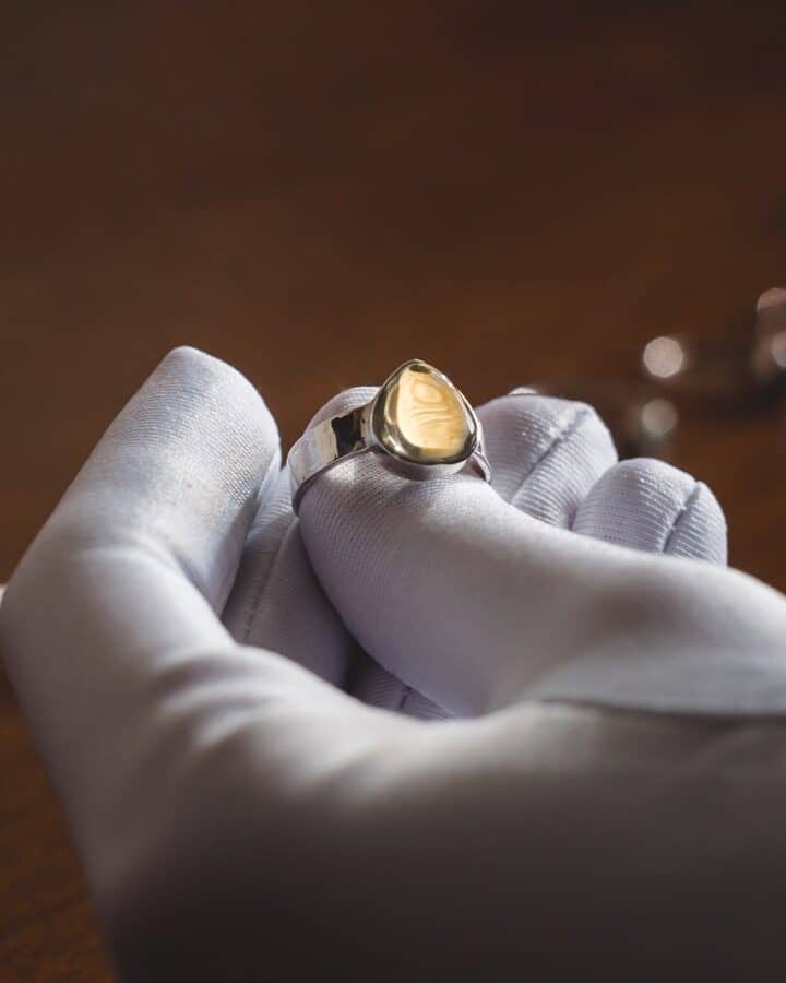 a jeweler examines a piece of jewelry in a white glove